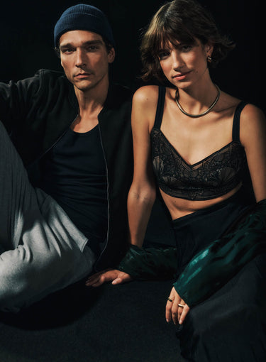 Two people sitting close together against a dark background. wearing Holly, Indra
